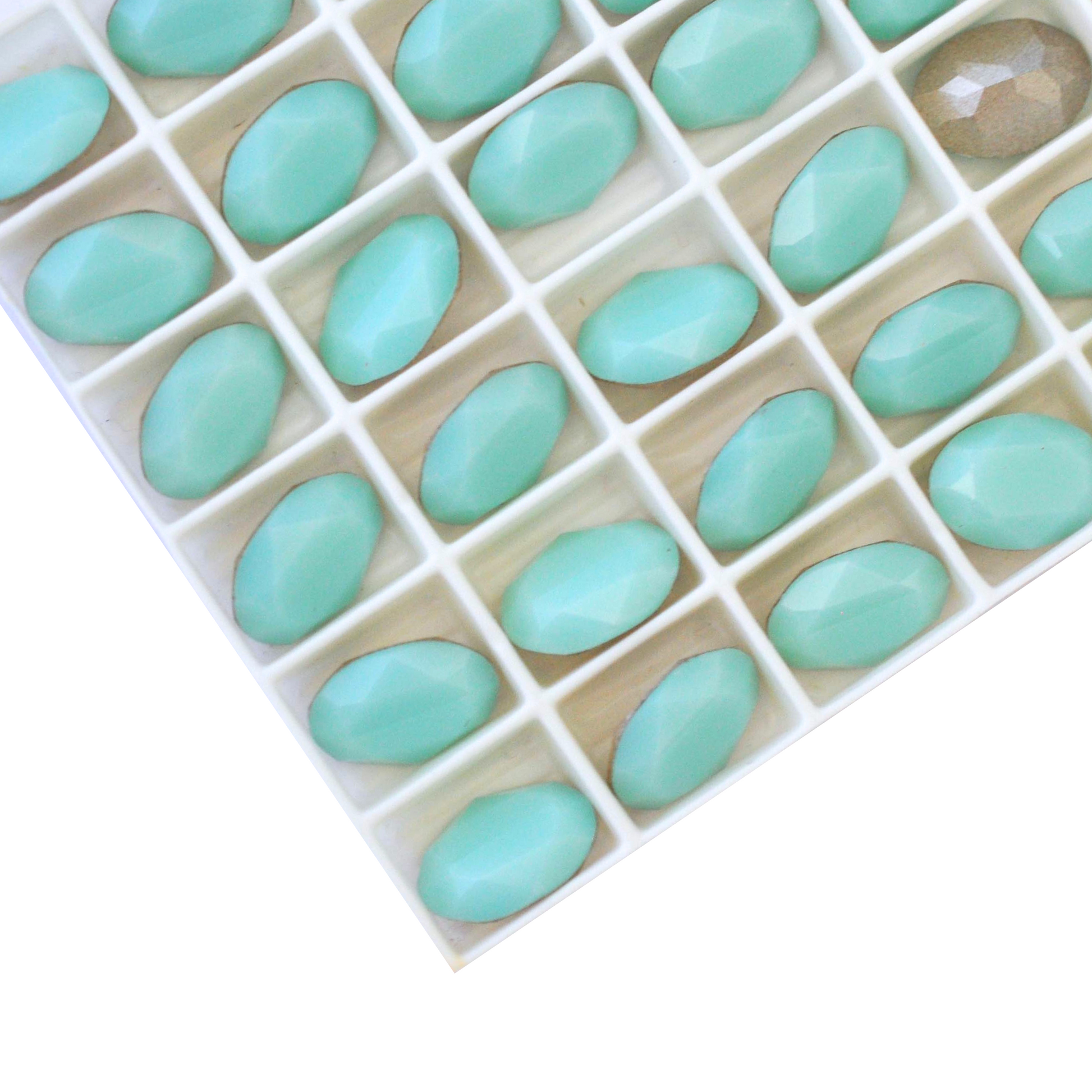 Oval shape faceted Austrian crystal rhinestones in the color Mint Alabaster displayed on a white background.