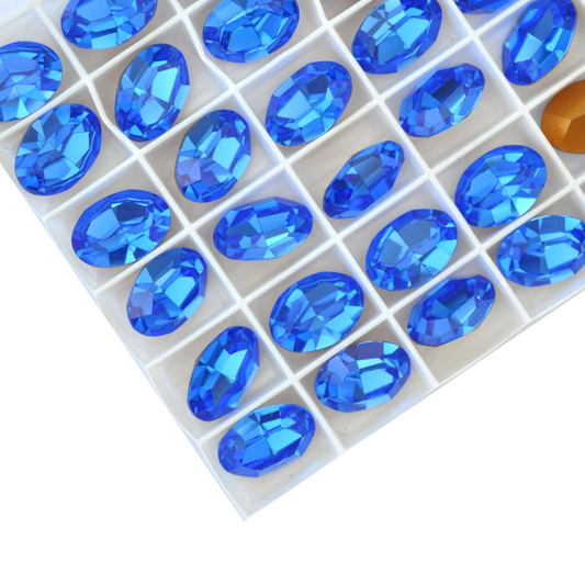 Oval shape faceted Austrian crystal rhinestones in the color Sapphire displayed on a white background.