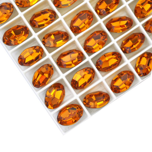 Oval shape faceted Austrian crystal rhinestones in the color Topaz displayed on a white background.