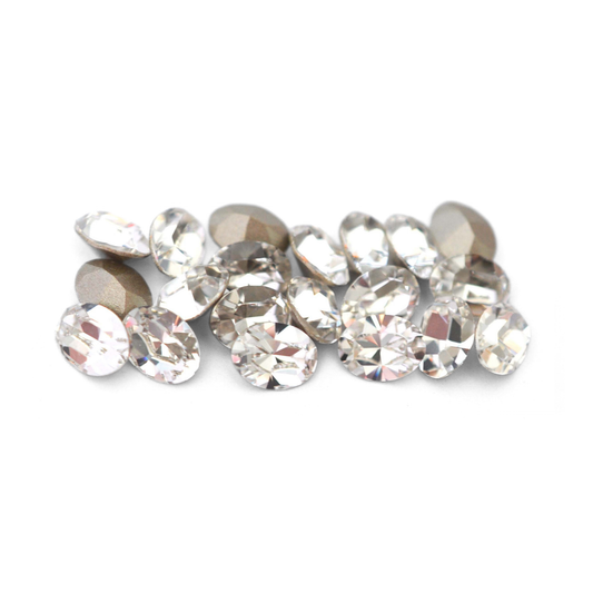Oval shaped faceted Austrian crystal rhinestones in the color Crystal displayed on a white background.