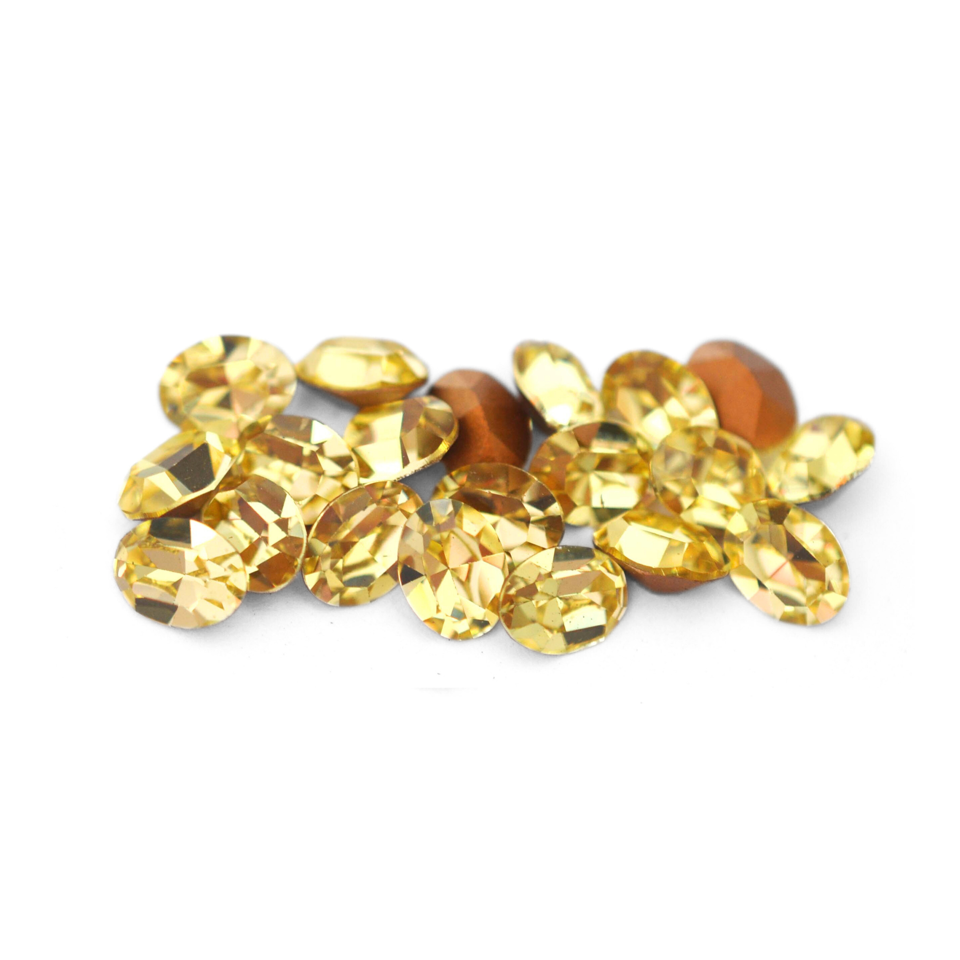Oval shaped faceted Austrian crystal rhinestones in the color Jonquil displayed on a white background.