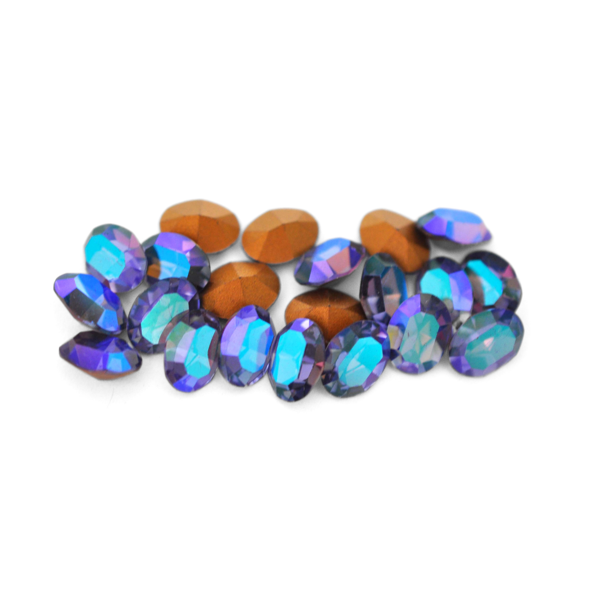 Oval shaped faceted Austrian crystal rhinestones in the color Tanzanite Glacier Blue displayed on a white background.