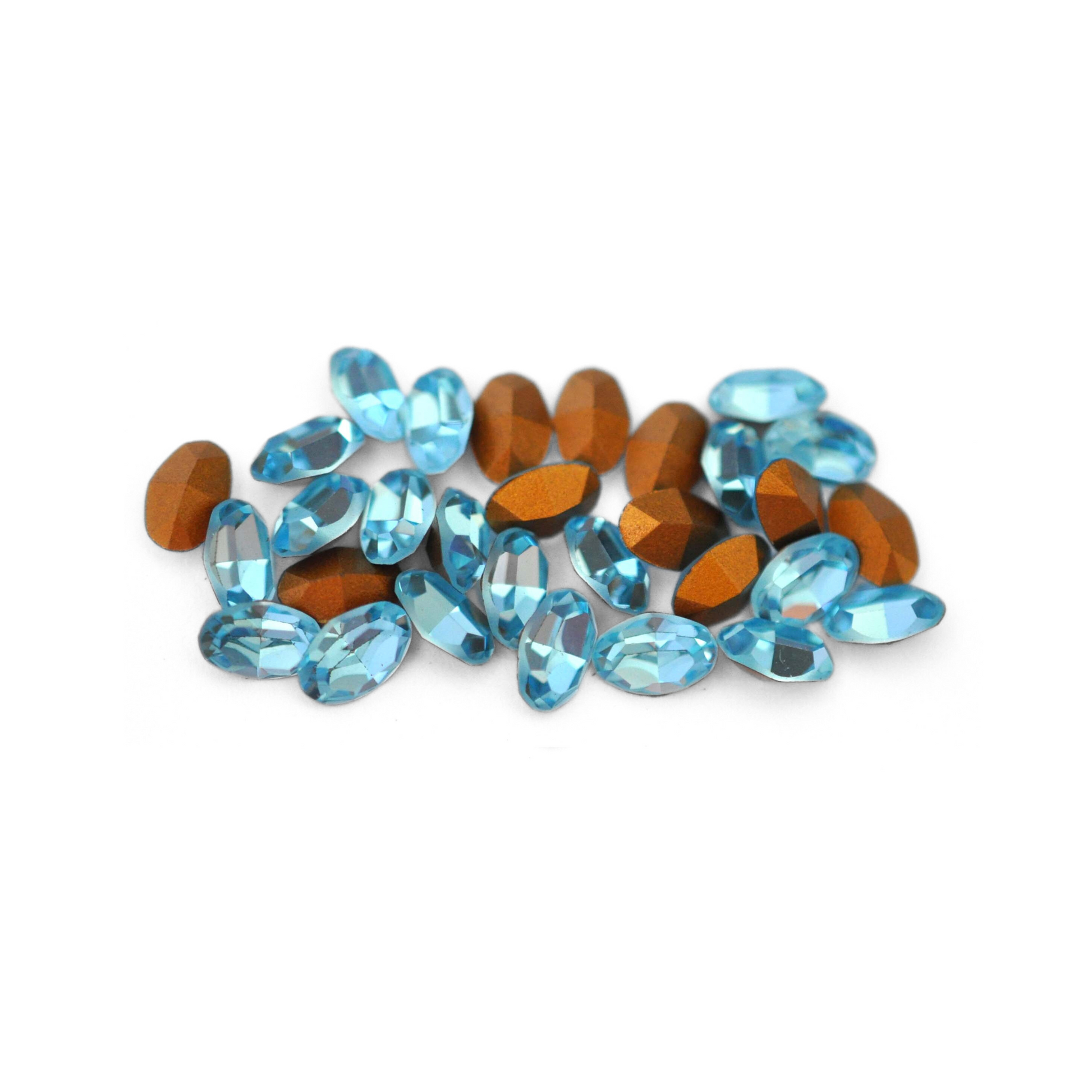 Oval shaped faceted Austrian crystal rhinestones in the color Aquamarine displayed on a white background.