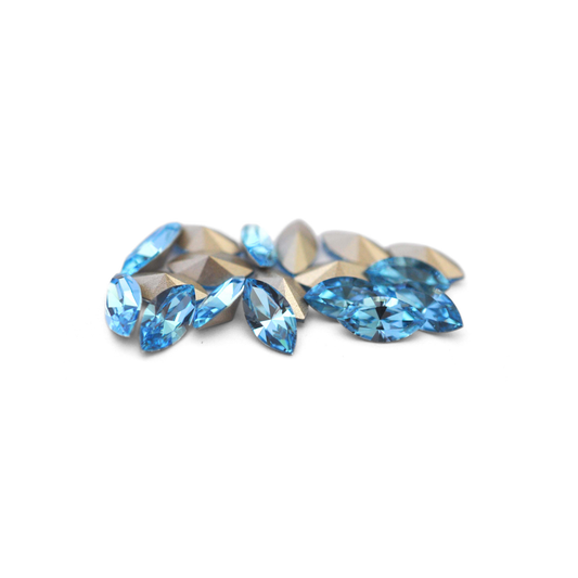 Navette shaped faceted Austrian crystal rhinestones in the color Aquamarine displayed on a white background.