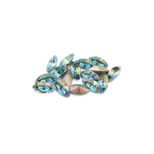 Navette shaped faceted Austrian crystal rhinestones in the color Aqua Champagne displayed on a white background.