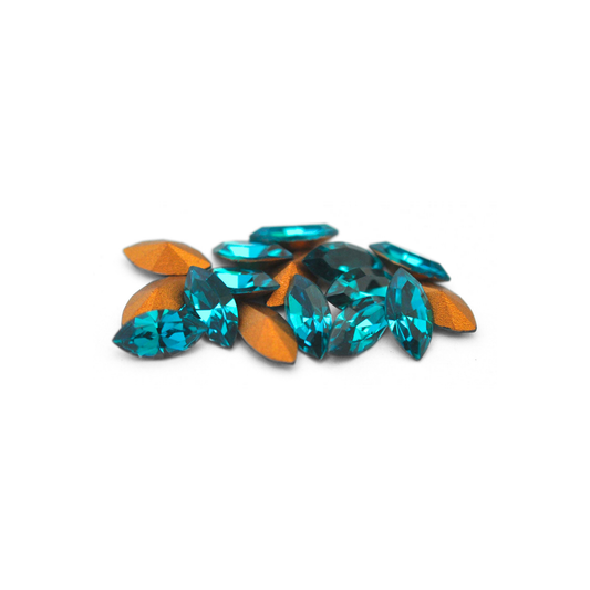 Navette shaped faceted Austrian crystal rhinestones in the color Blue Zircon displayed on a white background.