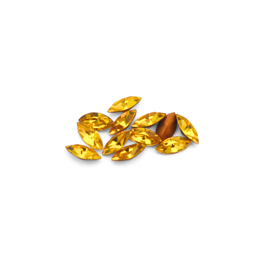 Navette shaped faceted Austrian crystal rhinestones in the color Citrine displayed on a white background.