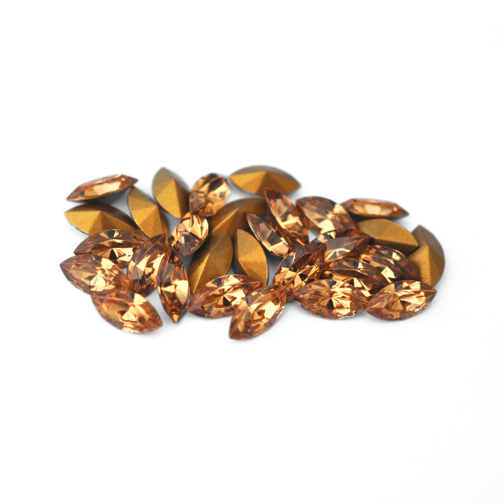 Navette shaped faceted Austrian crystal rhinestones in the color Light Colorado Topaz displayed on a white background.