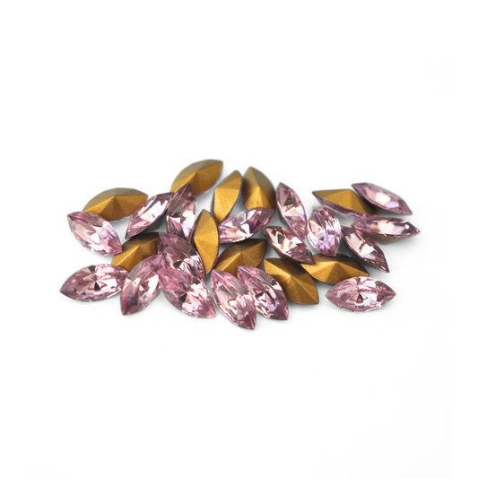 Navette shaped faceted Austrian crystal rhinestones in the color Light Amethyst displayed on a white background.