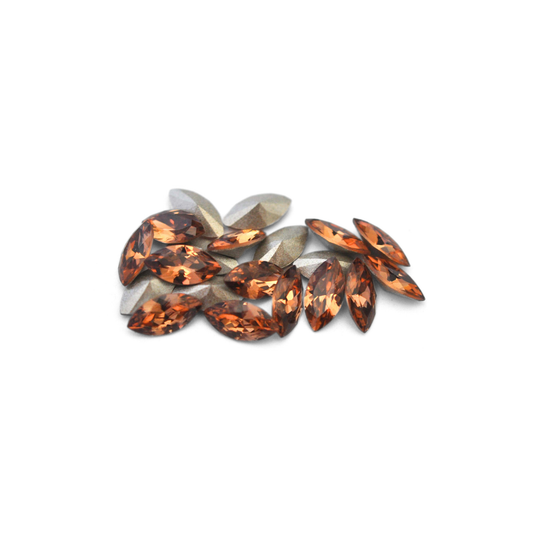 Navette shaped faceted Austrian crystal rhinestones in the color Light Smoked Topaz displayed on a white background.