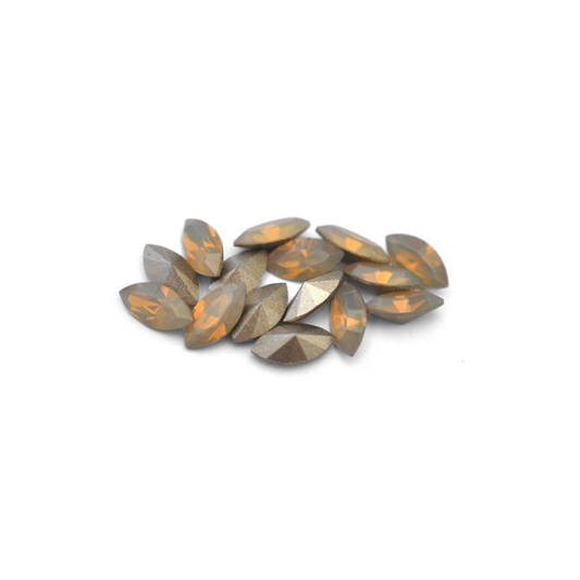 Navette shaped faceted Austrian crystal rhinestones in the color Sand Opal displayed on a white background.