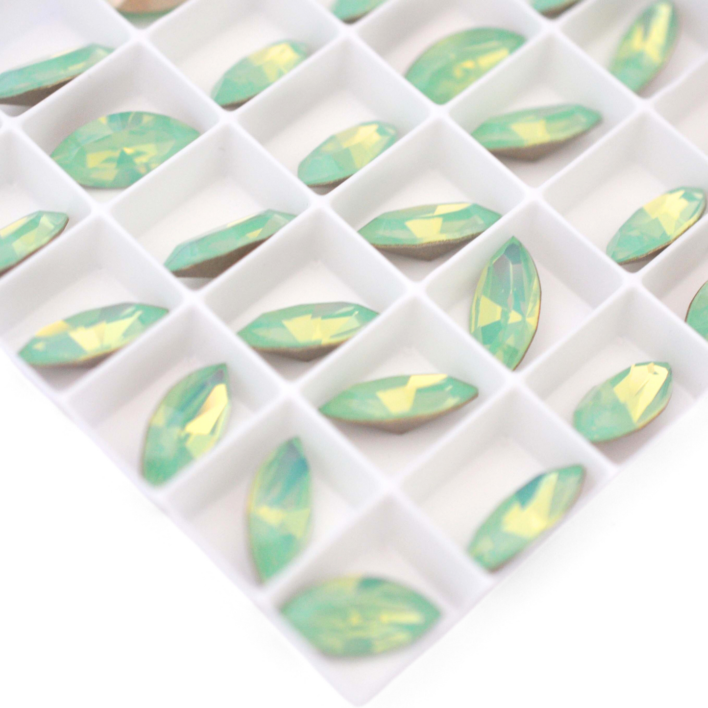 Navette shaped faceted Austrian crystal rhinestones in the color Chrysolite Opal displayed on a white background.