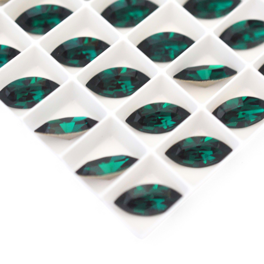 Navette shaped faceted Austrian crystal rhinestones in the color Emerald displayed on a white background.