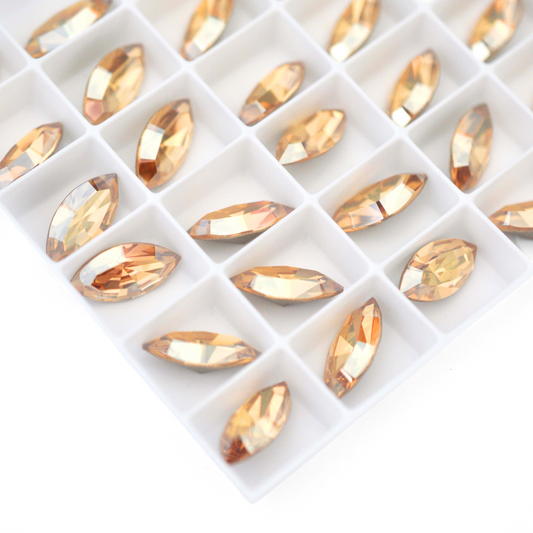 Navette shaped faceted Austrian crystal rhinestones in the color Golden Shadow displayed on a white background.