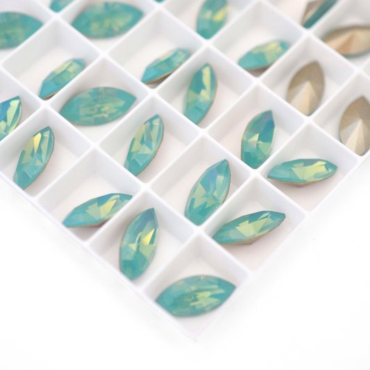 Navette shaped faceted Austrian crystal rhinestones in the color Pacific Opal displayed on a white background.