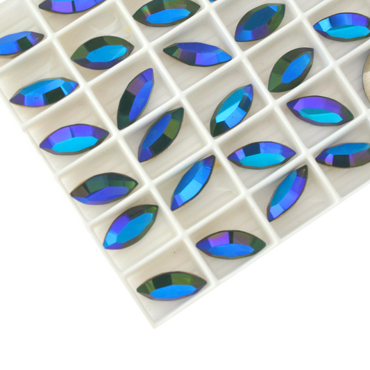 Navette shaped faceted Austrian crystal rhinestones in the color Palace Green Opal Glacier Blue displayed in a tray on a white background.