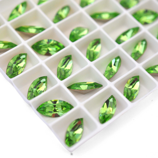 Navette shaped faceted Austrian crystal rhinestones in the color Peridot displayed on a white background.