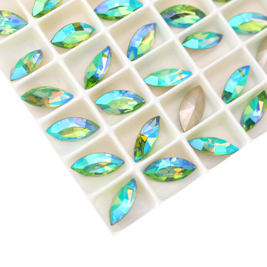 Navette shaped faceted Austrian crystal rhinestones in the color Peridot AB displayed in a tray on a white background.