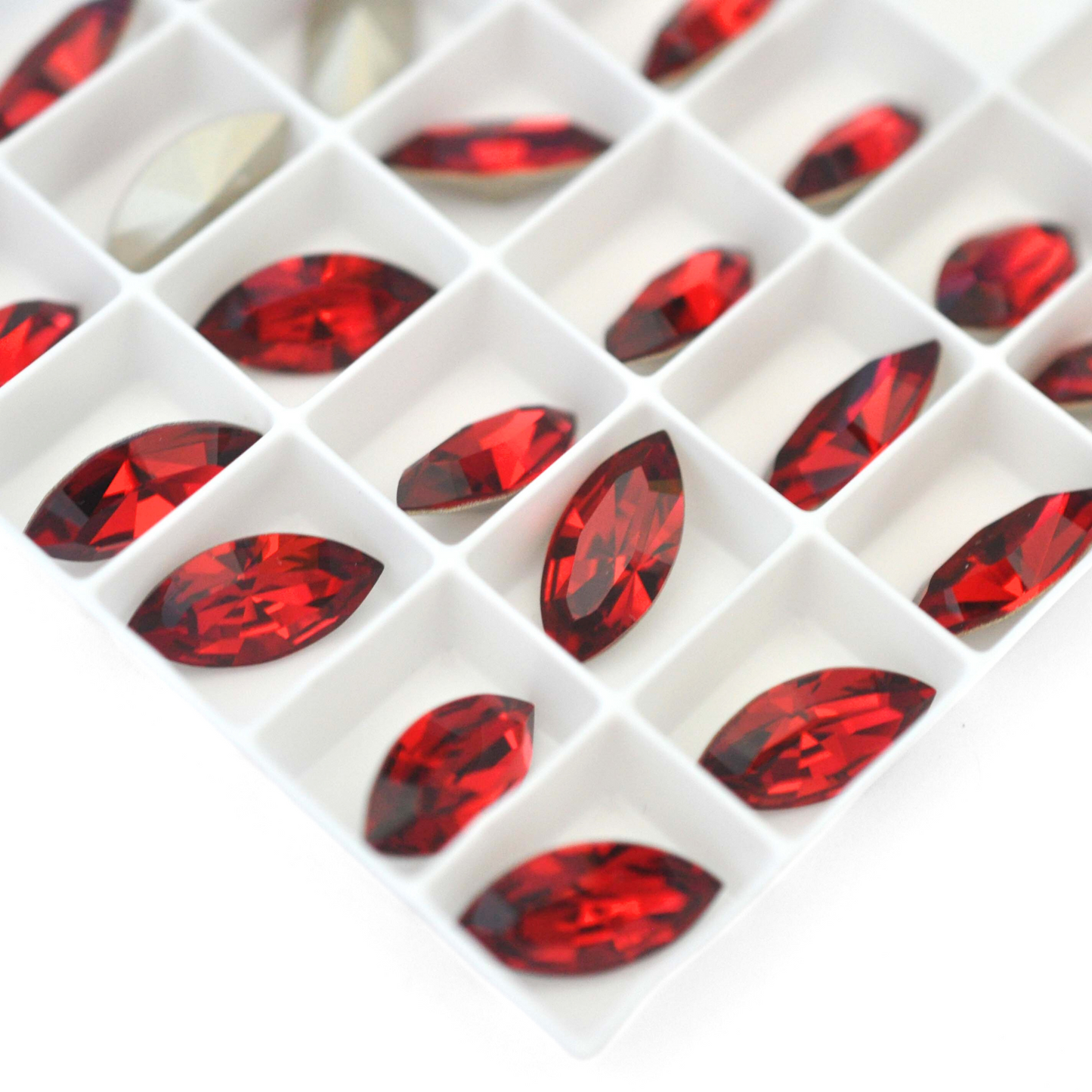 Navette shaped faceted Austrian crystal rhinestones in the color Scarlet displayed on a white background.