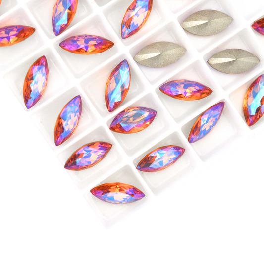 Navette shaped faceted Austrian crystal rhinestones in the color Topaz Glacier Blue displayed on a white background.