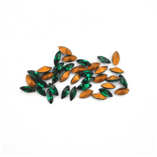 Navette shaped faceted Austrian crystal rhinestones in the color Emerald displayed on a white background.