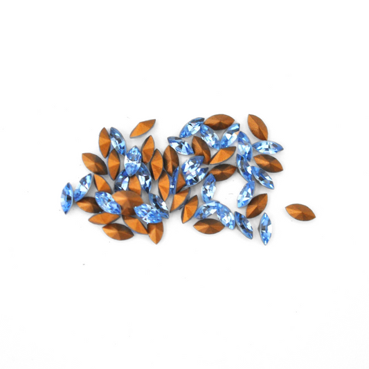Navette shaped faceted Austrian crystal rhinestones in the color Light Sapphire displayed on a white background.