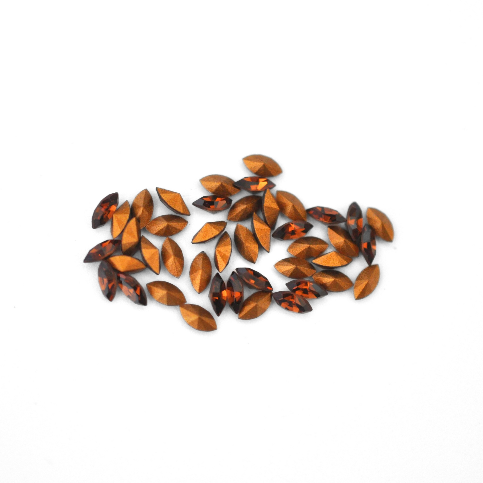Navette shaped faceted Austrian crystal rhinestones in the color Smoked Topaz displayed on a white background.