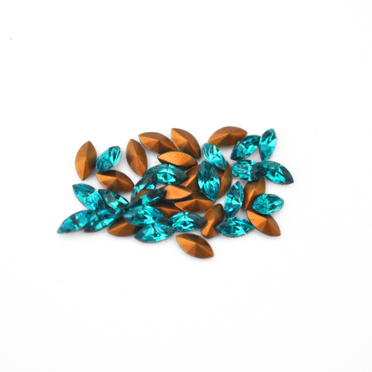 Navette shaped faceted Austrian crystal rhinestones in the color Blue Zircon displayed on a white background.
