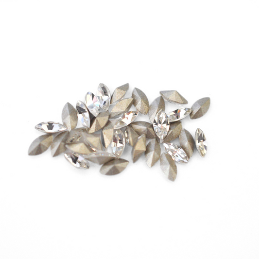 Navette shaped faceted Austrian crystal rhinestones in the color Crystal displayed on a white background.