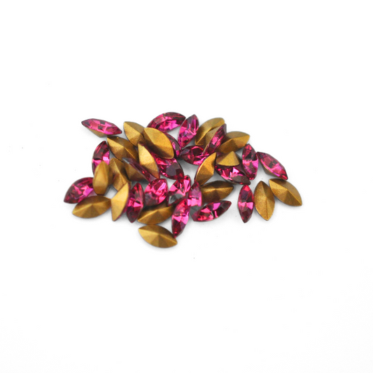Navette shaped faceted Austrian crystal rhinestones in the color Fuchsia displayed on a white background.