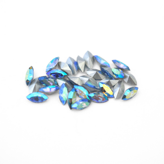 Navette shaped faceted Austrian crystal rhinestones in the color Light Sapphire AB displayed on a white background.