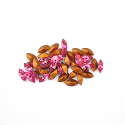 Navette shaped faceted Austrian crystal rhinestones in the color Rose displayed on a white background.