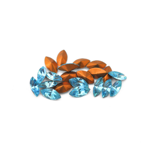 Navette shaped faceted Austrian crystal rhinestones in the color Aquamarine displayed on a white background.