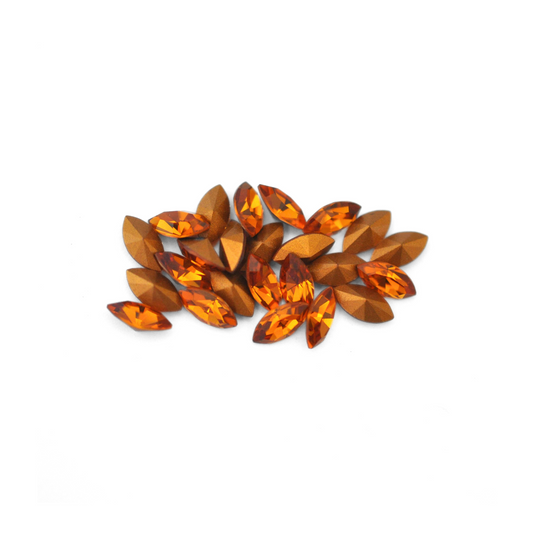 Navette shaped faceted Austrian crystal rhinestones in the color Topaz displayed on a white background.
