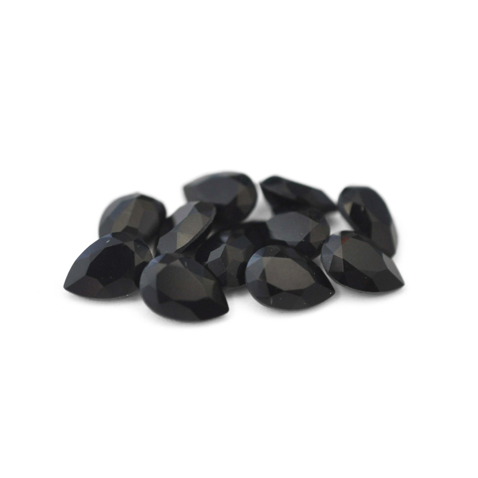 Pear shaped faceted Austrian crystal rhinestones in the color Jet displayed on a white background.