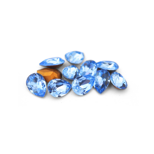 Pear shaped faceted Austrian crystal rhinestones in the color Light Sapphire displayed on a white background.