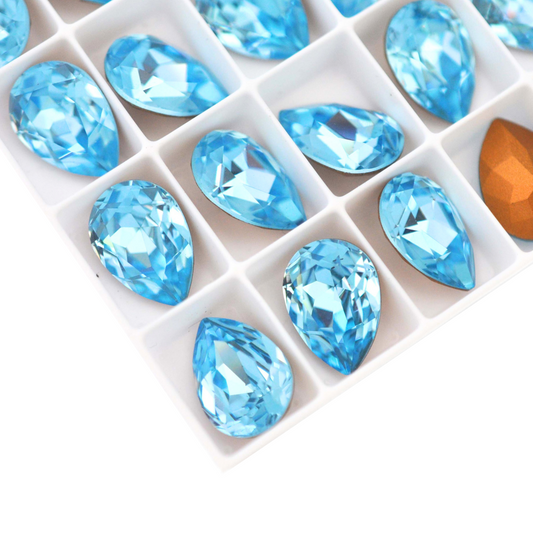 Pear shape faceted Austrian crystal rhinestones in the color Aquamarine displayed on a white background.