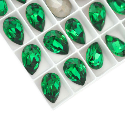 Pear shape faceted Austrian crystal rhinestones in the color Majestic Green displayed on a white background.