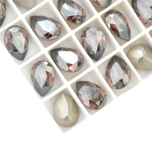 Pear shape faceted Austrian crystal rhinestones in the color Vintage Rose Satin displayed on a white background.