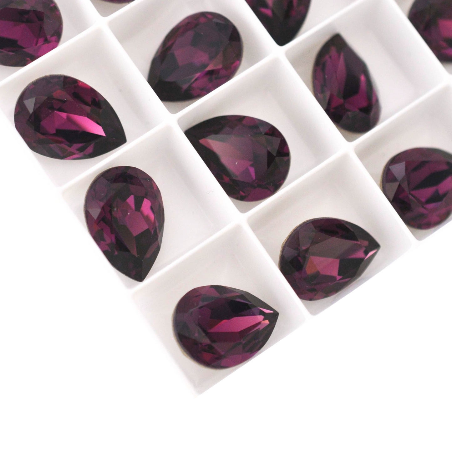 Pear shape faceted Austrian crystal rhinestones in the color Amethyst displayed on a white background.