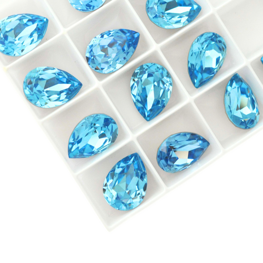 Pear shape faceted Austrian crystal rhinestones in the color Aquamarine displayed on a white background.