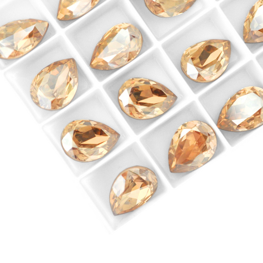Pear shape faceted Austrian crystal rhinestones in the color Golden Shadow displayed on a white background.