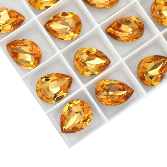 Pear shape faceted Austrian crystal rhinestones in the color Golden Topaz displayed on a white background.