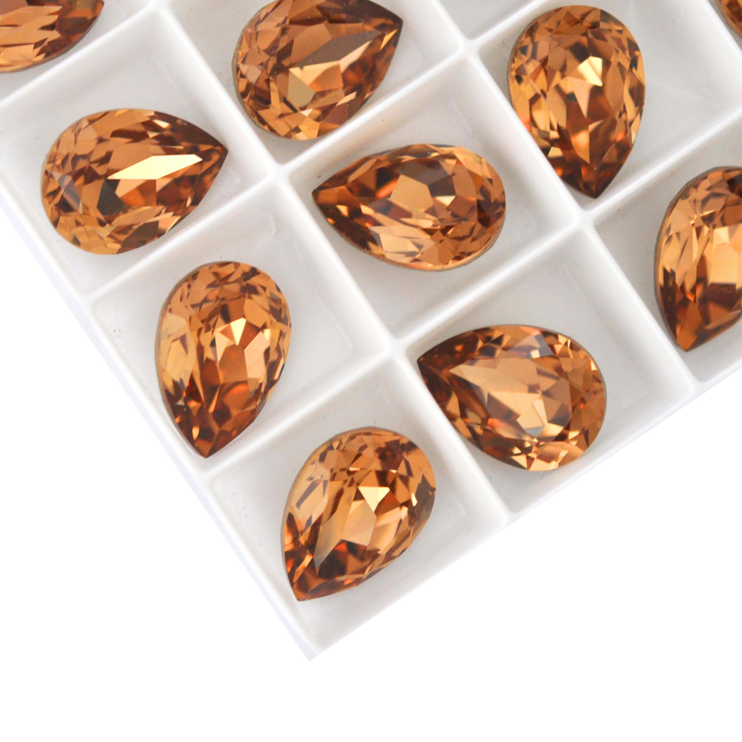 Pear shape faceted Austrian crystal rhinestones in the color Light Smoked Topaz displayed on a white background.