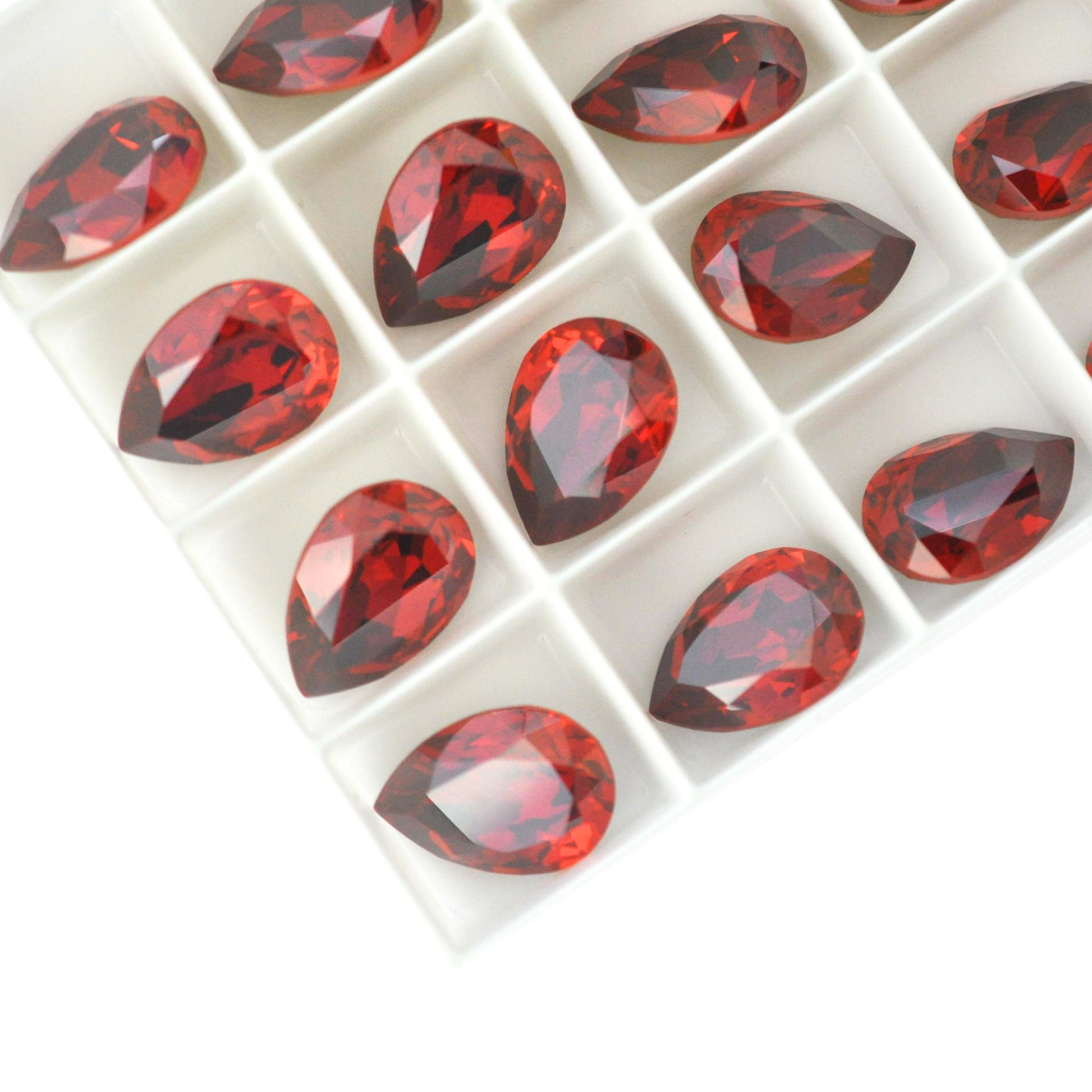 Pear shape faceted Austrian crystal rhinestones in the color Red Magma displayed on a white background.