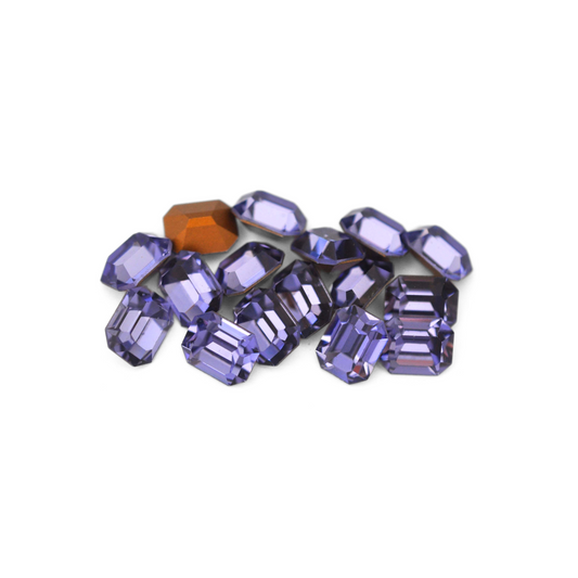 Octagon shaped faceted Austrian crystal rhinestones in the color Tanzanite displayed on a white background.