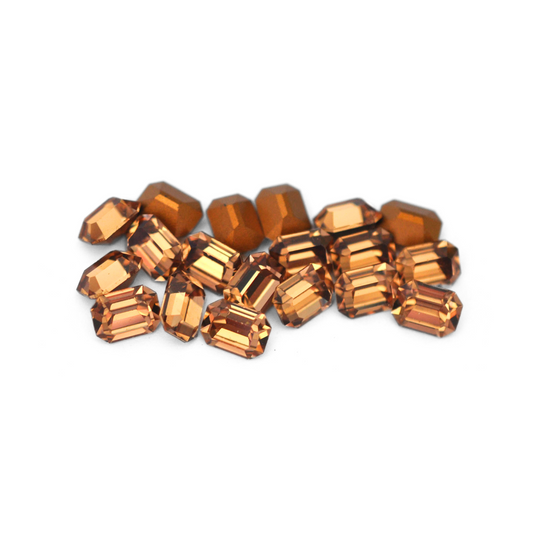 Octagon shaped faceted Austrian crystal rhinestones in the color Light Colorado Topaz displayed on a white background.