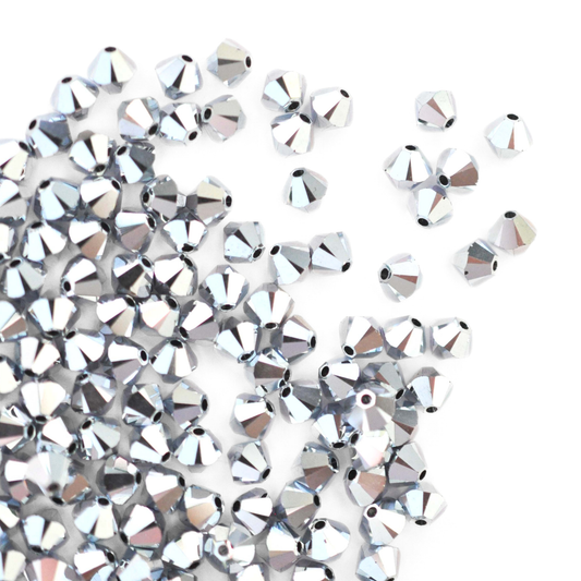 Austrian crystal 5328 bicone beads in the color CAL 2X spilling out onto a white background.