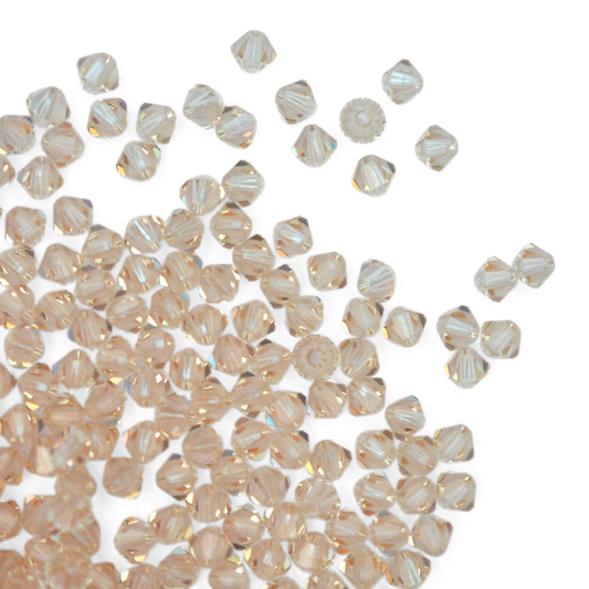 Austrian crystal 5328 bicone beads in the color Cantaloupe spilling out onto a white background