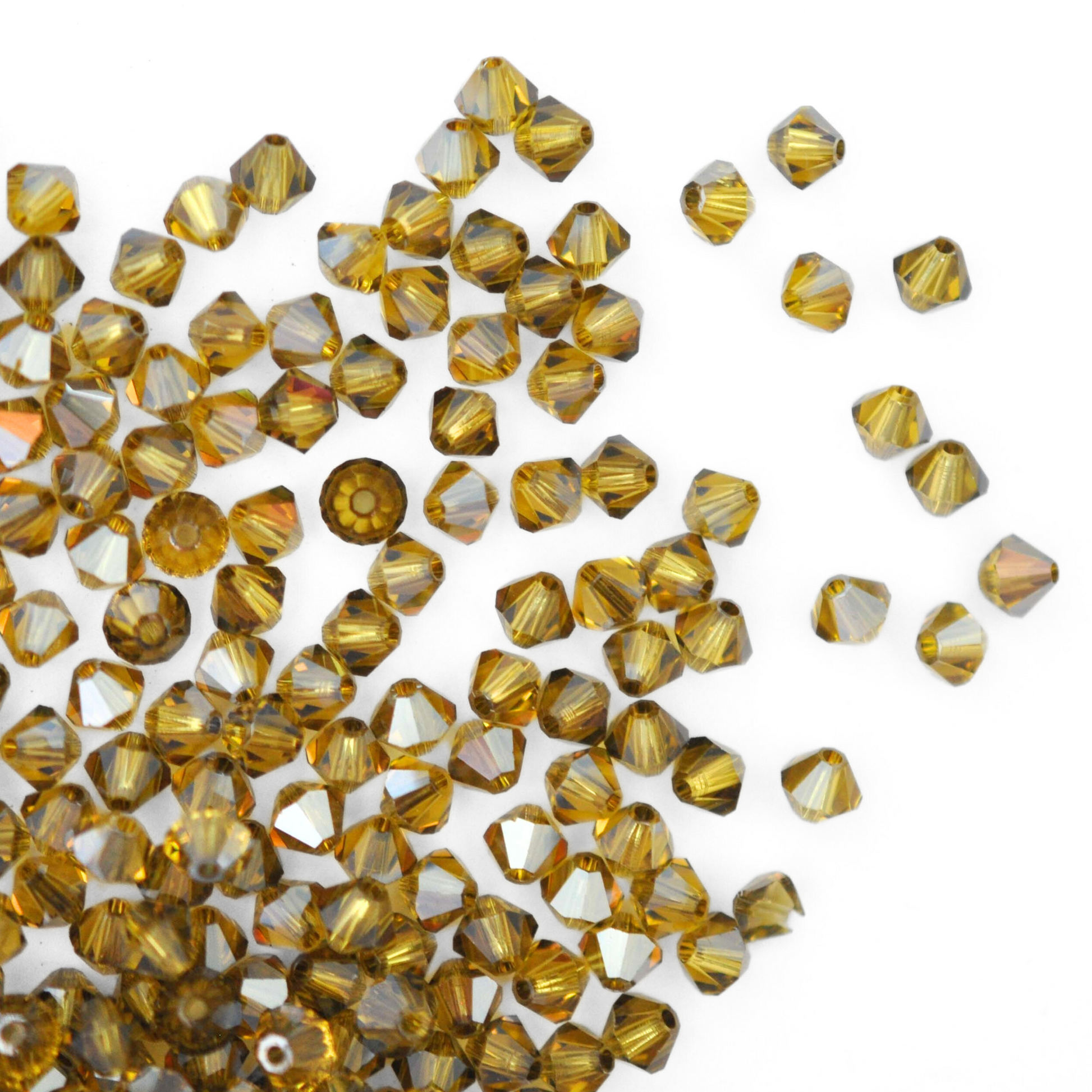 Austrian crystal 5328 bicone beads in the color Light Topaz Satin spilling out onto a white background.